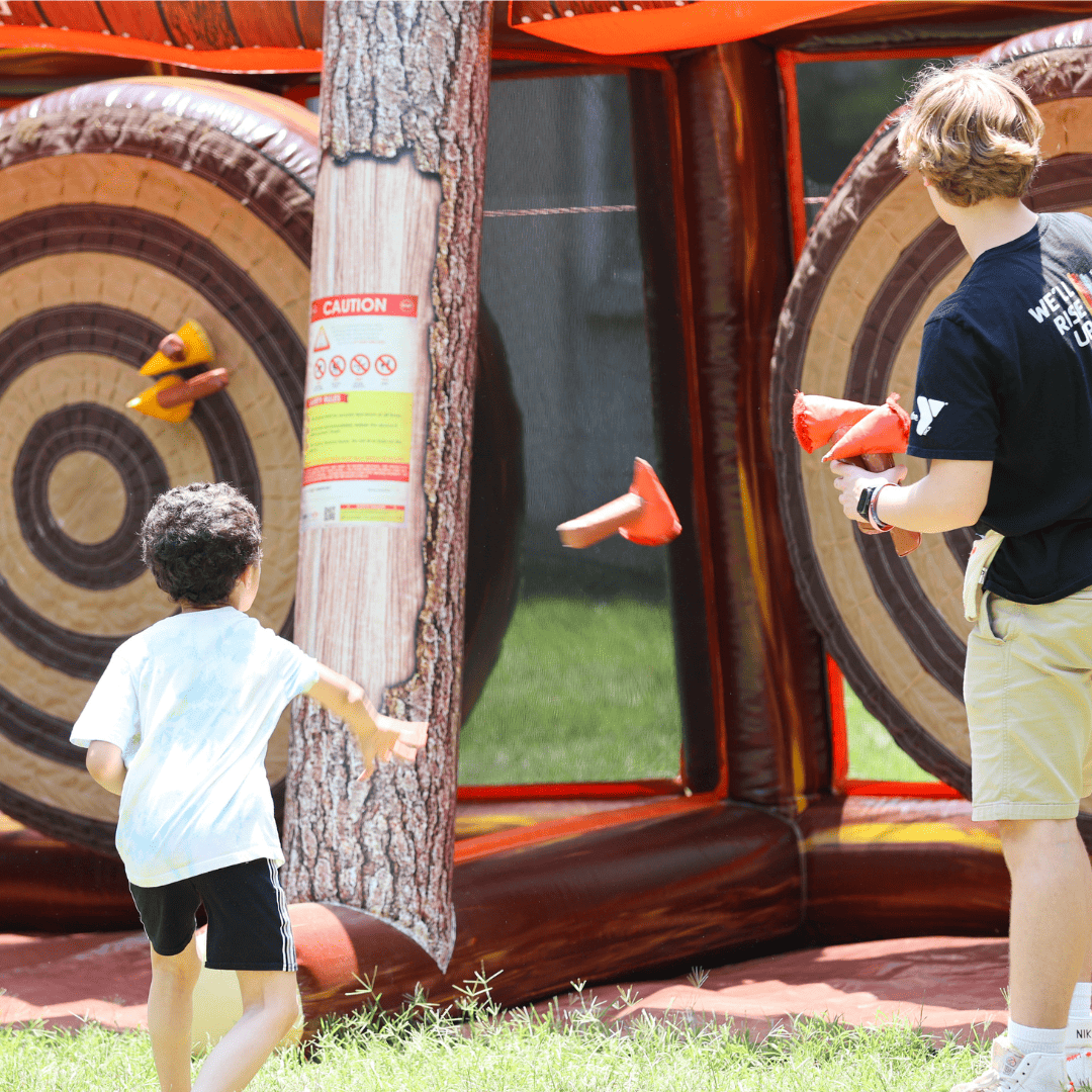 young boy throwing an axe at a large target in the Kid Zone